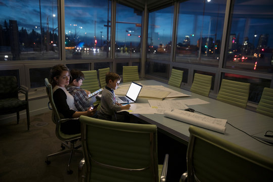 Dedicated Mother Architect Working Late With Sons Coloring In Dark Conference Room