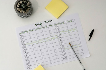 Flat lay image of weekly planner with stationary scattered around. Revision timetable for exams or...