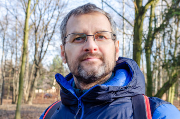 Portrait of a middle-aged man in down jacket in the barren forest