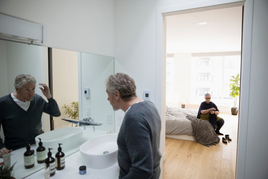 Senior man checking hair in bathroom mirror