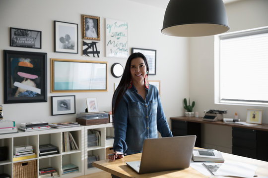 Portrait confident, creative businesswoman entrepreneur working at laptop in studio office