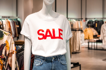 Mannequin of a woman in a white shirt and jeans with a red inscription sale in a clothing store. Promotion, advertising, shopping and black friday concept