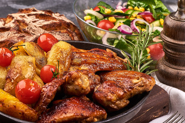 Delicious Roasted chicken wings with baked potatoes on rustic background