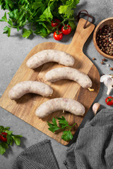 Sausage with spices and thyme on a white plate on the gray kitchen table. Top view with space for text