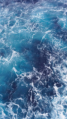 Dark water of the pacific ocean. Natural blue background. foam composition in the ocean. white sea foam, waves, storm. vertical photo