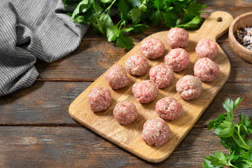 Raw meat meatballs on a wooden Board on a brown wooden table. Top view with a copy of the space	