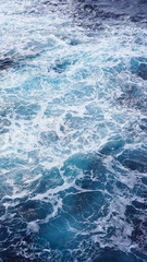 Fototapeta na wymiar Dark water of the pacific ocean. Natural blue background. foam composition in the ocean. white sea foam, waves, storm. vertical photo