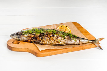Grilled mackerel served with lemon served on a wooden board shot on a white background