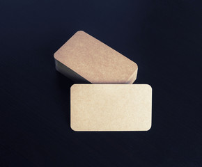 Brown paper business cards on black wooden background. Mockup for branding identity.