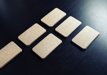Blank brown paper business cards on black wood table background.