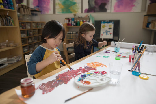Preschool boy and girl painting in art class