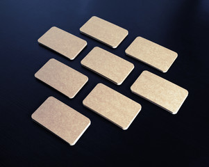 Blank kraft paper business cards on black wood table background. Mockup for branding identity.