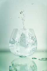 Ice cube splashing in clear water glas with white background