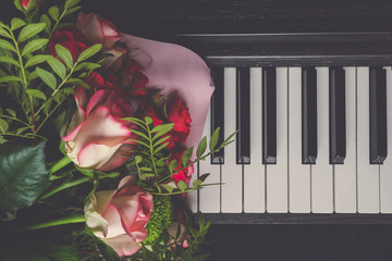flat lay Closeup piano key on a wooden table with selective focus, and a bouquet of flowers,...
