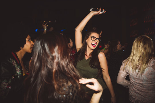 Happy, exuberant young millennial woman dancing, partying at nightclub