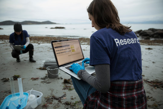 Eco-friendly female scientist with laptop on beach