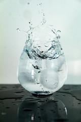water splash in glass because of ice cube infront of white background