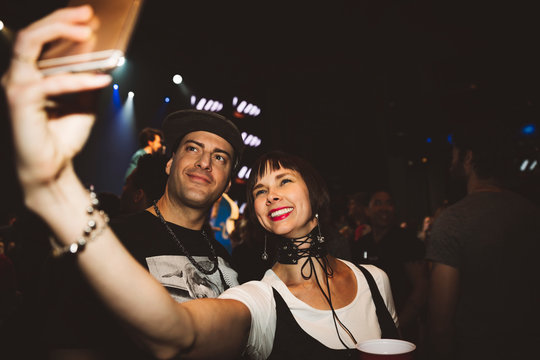 Happy couple taking selfie with camera at nightclub