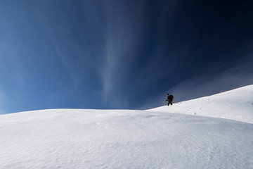 Naklejka na ściany i meble Hiker is walking on the winter trail against blue sky background. minimalist style