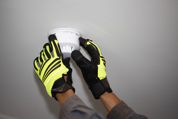 Certified inspector wearing safety glove conducting yearly inspecting safety house fire alarm...