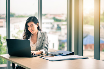 Fototapeta premium Happy attractive Asian business woman working with a laptop and financial document at office, successful action, Business concept.
