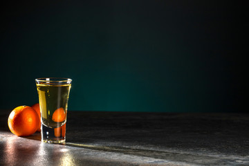 Shot of whiskey and two tangerines on a beautiful dark green background. Copy space.