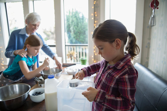 Girl baking with sister and grandmother in kitchen