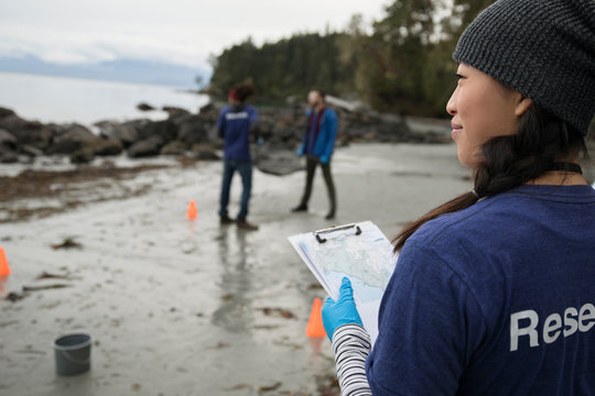 Eco-friendly female scientist with clipboard on beach