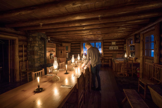 Woman Preparing Candlelight Dining Table In Ski Resort Lodge