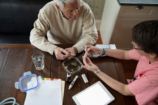Home caregiver explaining medicinal marijuana to senior man