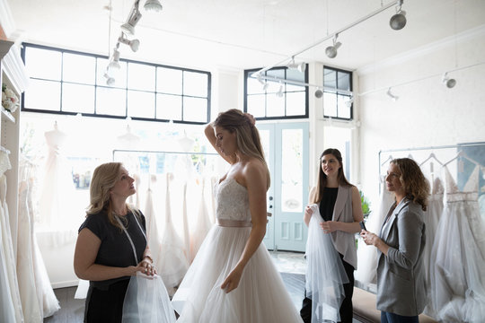 Bride and friends at wedding dress fitting in bridal boutique