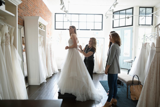 Bride and friends at wedding dress fitting in bridal boutique