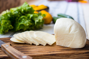 Suluguni slices - salty Georgian traditional cheese on wooden board.