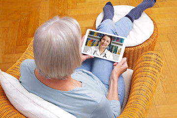 telemedicine concept, old woman with tablet pc during an online consultation with her doctor in her living room. - obrazy, fototapety, plakaty