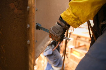 Worker wearing a glove using socket fastening nut attached into the structure metal wall, construction mine site, Perth, Australia