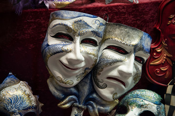 Two large colored masks on a white background, joined together. One concept of sadness the other concept of joy. Venetian carnival handmade product in Italy.