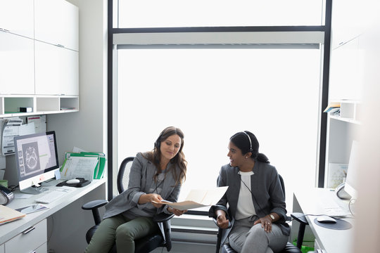 Female Doctors Discussing Medical Record In Clinic Office