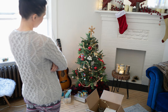 Young woman decorating apartment Christmas tree