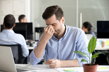 Male employee massage eyes having eye tension at workplace