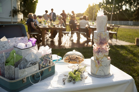 Tiered wedding cake, gifts and flowers on patio table