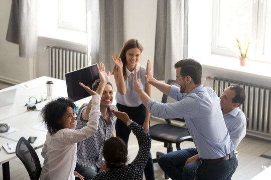Diverse young colleagues give high five engaged in teambuilding