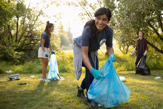 Smiling Woman Volunteering, Cleaning Up Garbage In Park