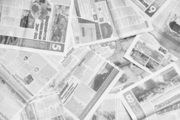 Lots of old newspapers on horizontal surface. Background texture, top view, blurred
