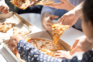Close up of employees eating pizza spend work break together