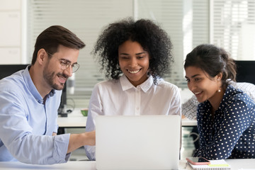 Multiracial happy colleagues talk working together on laptop