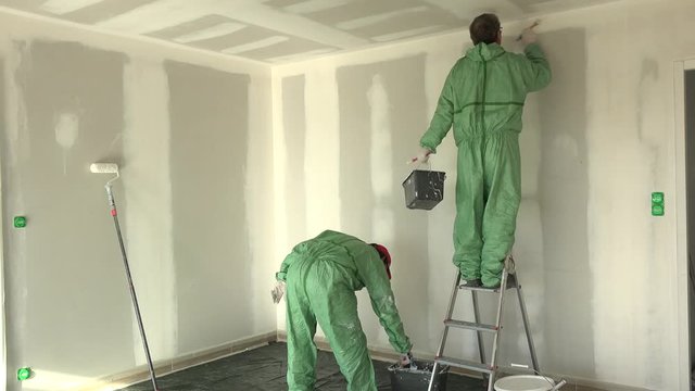 Time lapse two painters painting wall whith and ceiling in new house