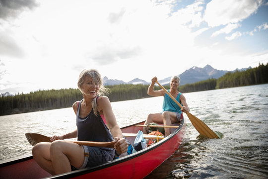 Happy Mature Couple Canoeing On Sunny Lake, Alberta, Canada