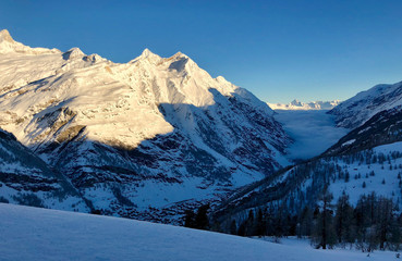 Matter valley and snowy mountains sunset view winter landscape Swiss Alps light clouds in the valley