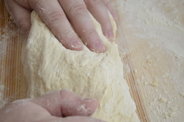 cook kneads pizza dough with his hands