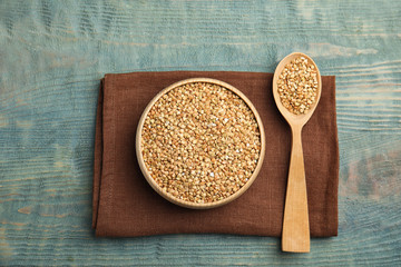 Uncooked green buckwheat grains on light blue wooden table, flat lay